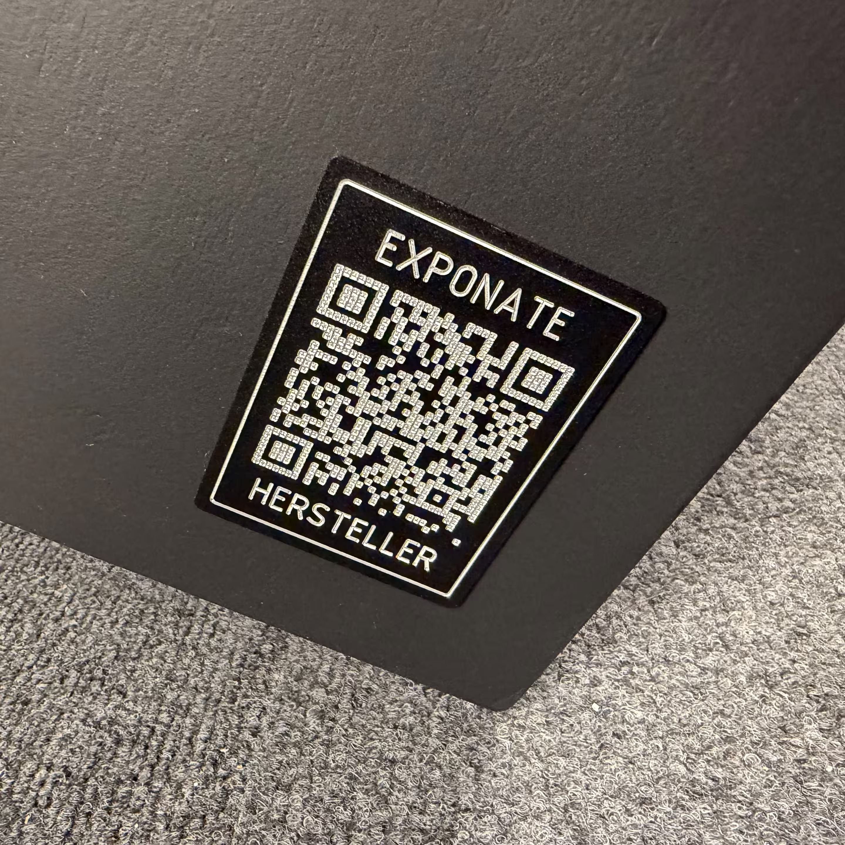 Eingravierter QR-Code auf schwarz beschichteter Aluminiumplatte am Messeexponat mit Link zur Projektseite